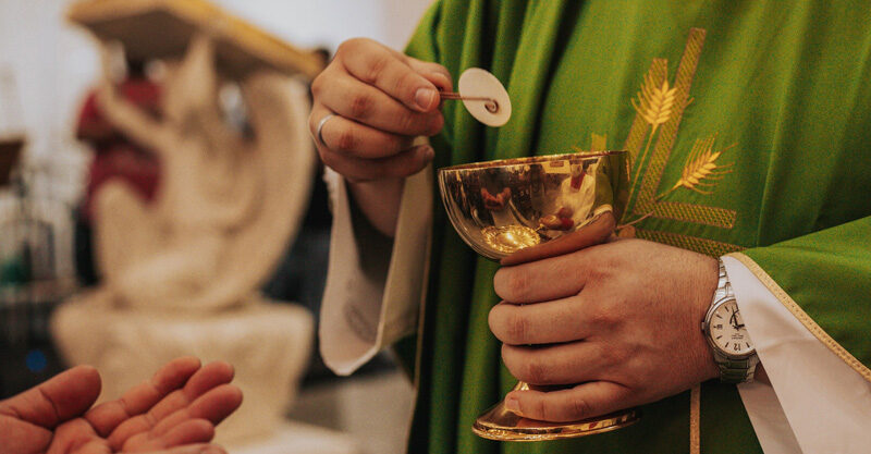 Padre distribuindo a sagrada comunhão na missa