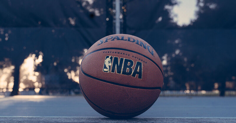 Bola de basquete com o logo da NBA desenhado, no chão da quadra