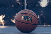Bola de basquete com o logo da NBA desenhado, no chão da quadra